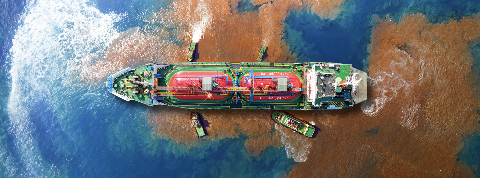 Image of a ship with oil leak in the sea and rescue ships around